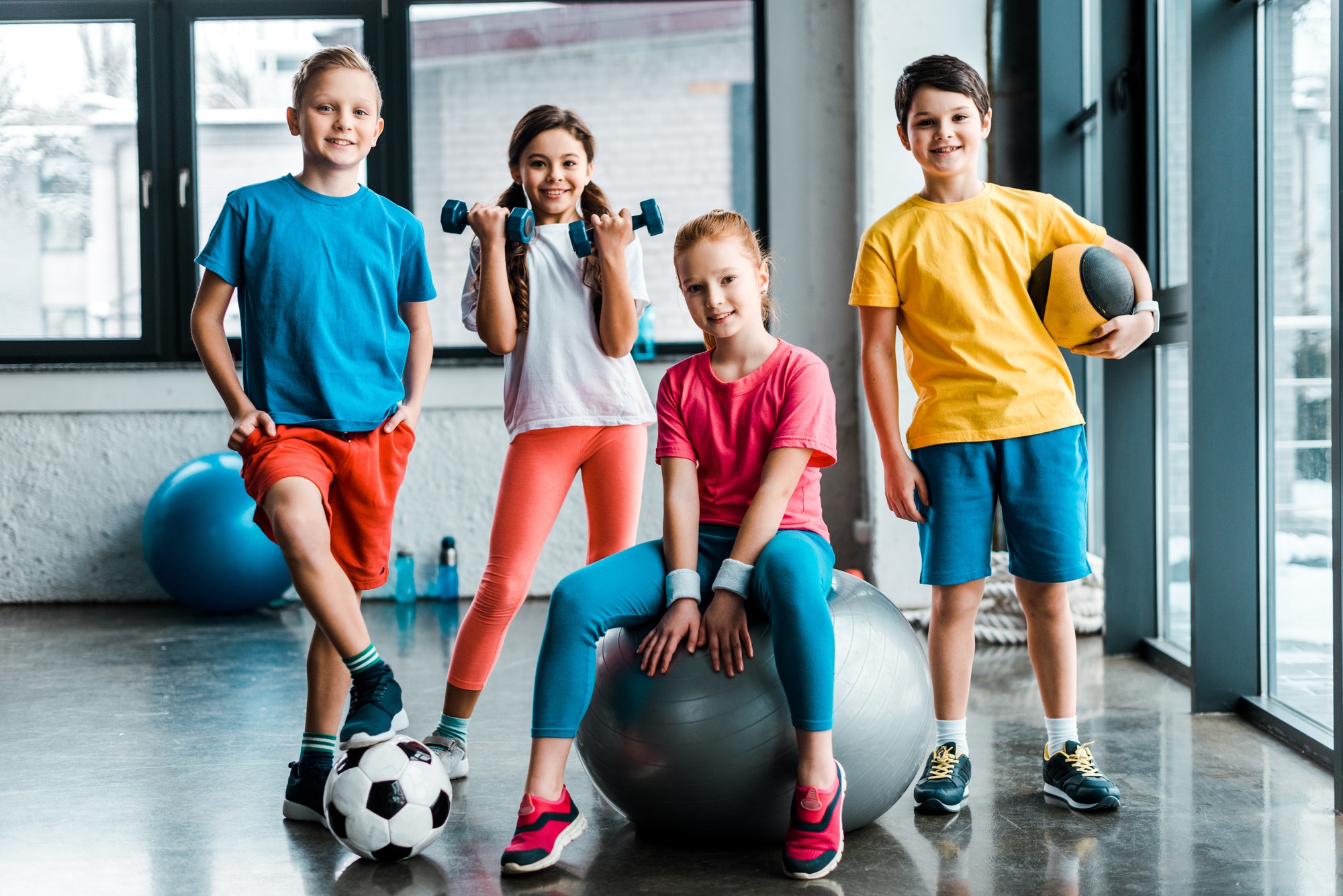 Laughing preteen kids posing with sport equipment Laughing preteen kids posing with sport equipment