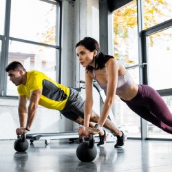 sportsman and sportswoman doing plank on weights in sports center sportsman and sportswoman doing plank on weights in sports center